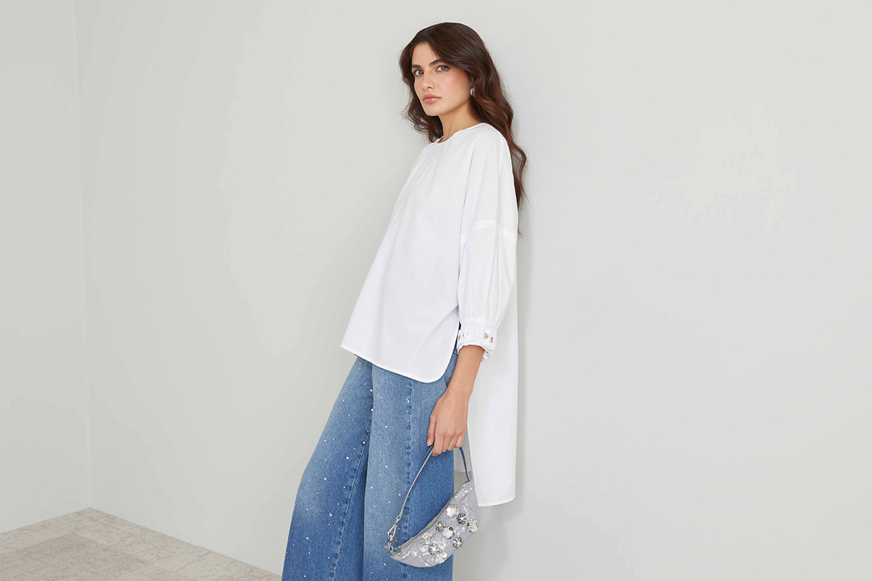 Modella indossa jeans con strass e maxi camicia di colore bianco.